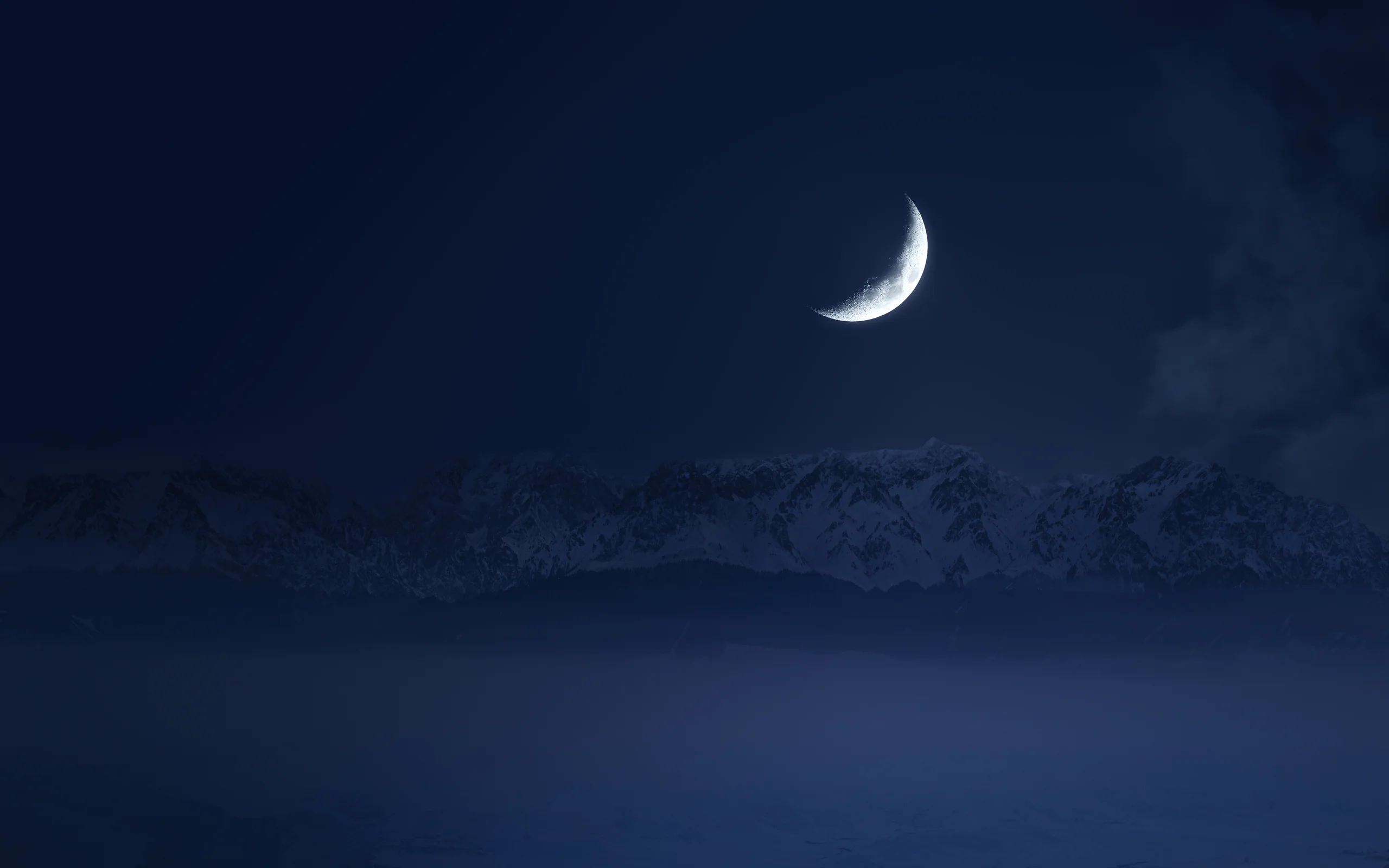 The moon suspended above mountains and a deep valley